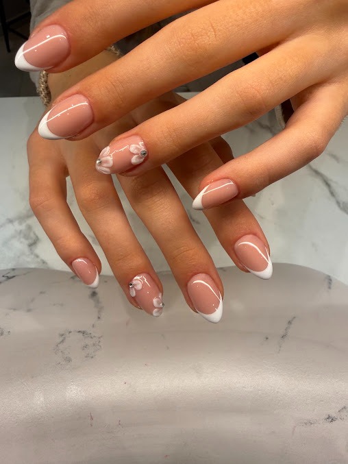 Klassieke French manicure met bloemendetail op marble ondergrond