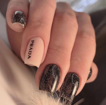 Luxury nail art — dark glitter met logo detail